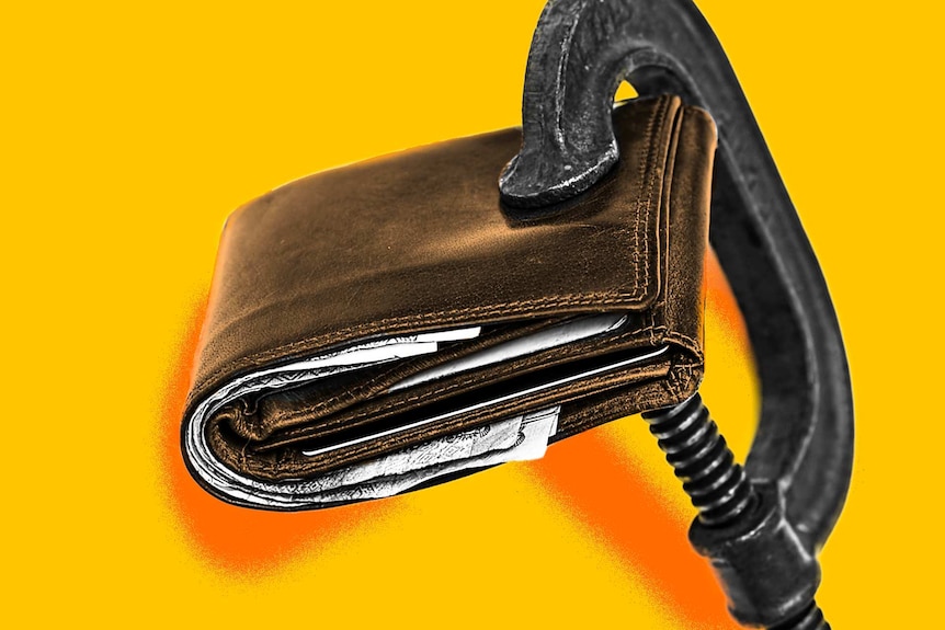 A wallet is held in a clamp against a yellow background.