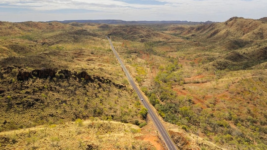 An aerial view of a road running through outback mountains