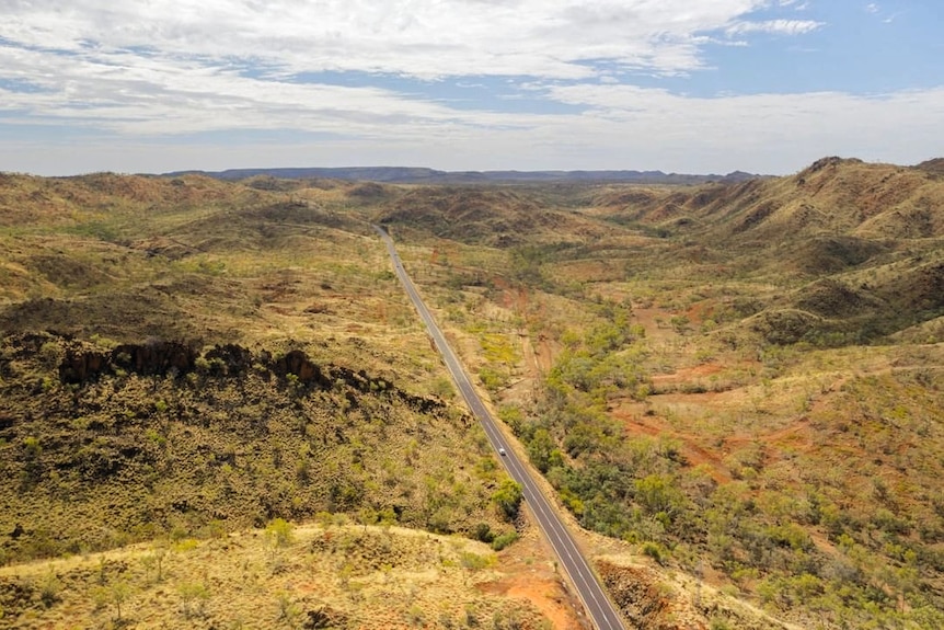 An aerial view of a road running through outback mountains.
