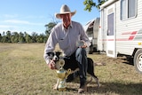 Dick Chapman kneels with his dog Panda while holding a belt buckle and trophy.