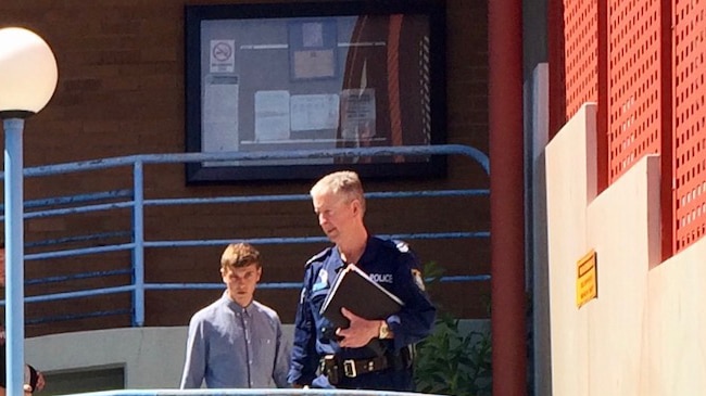 Police man escorting charged tourist out of Port Macquarie courthouse.