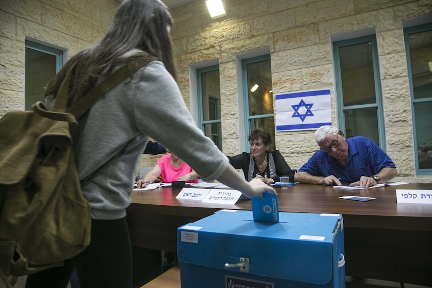 An Israeli citizen casts her vote at a polling station during legislative elections in Tel Mond.