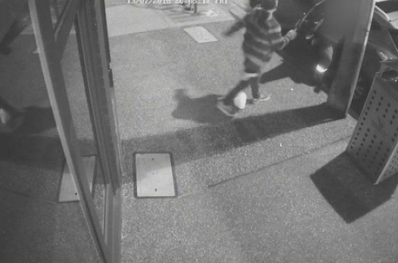A black-and-white CCTV image of a man in a striped shirt attacking an off-duty paramedic.