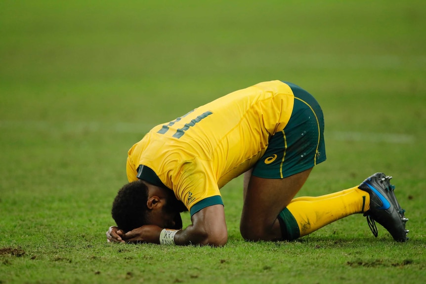 A Wallabies player holds in his head in his hands as he reflects on the loss to England at the Rugby World Cup.