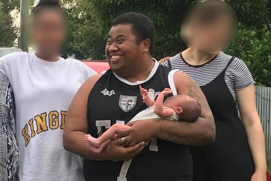 Max Lasea Tavai holds a baby in a family photo.