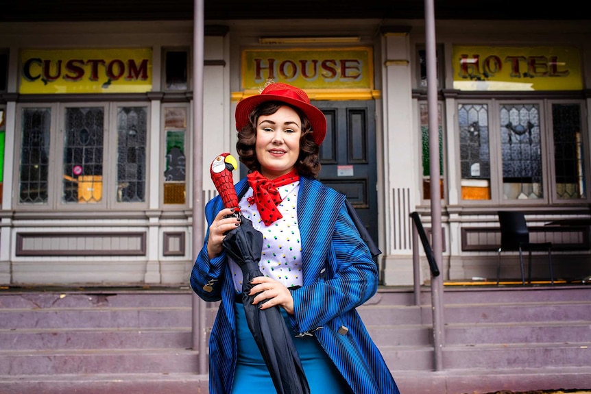 Young woman dressed as Mary Poppins outside old building.