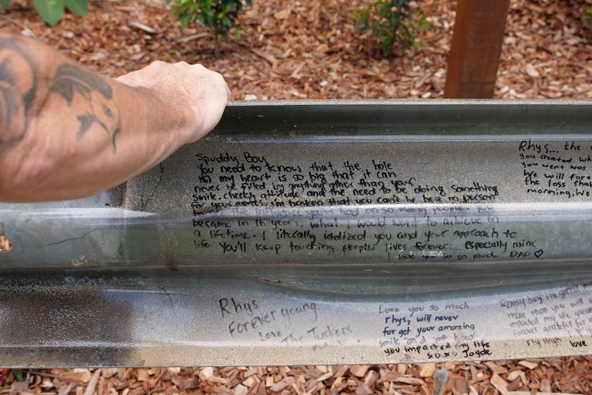 Guard rail from the bridge with tribute messages written on it in a memorial gardent to honour Rhys Yore.