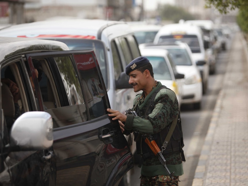 A police trooper checks a car at a checkpoint on the road leading to Sanaa International Airport.