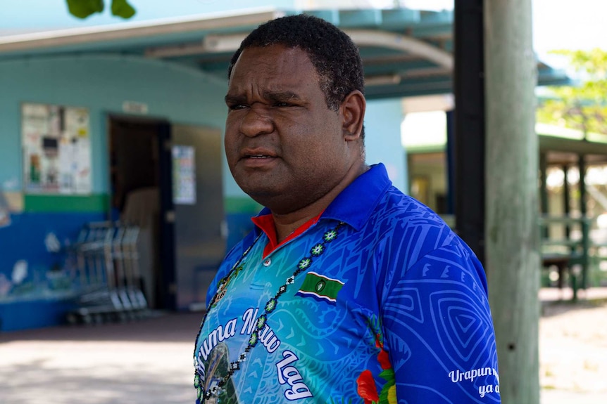 A man looking away from the camera, standing outdoors.