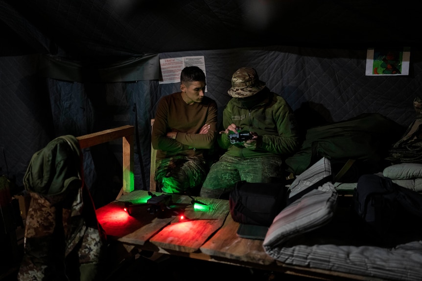 Ukrainian soldiers sit in a room and prepare a drone to use during military exercises