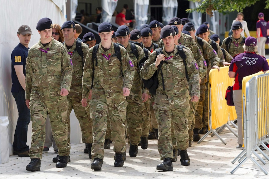 A group of British soldiers carrying packs march through London during the 2012 Olympics.