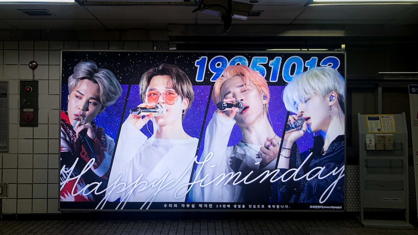 A brightly-coloured poster of K-pop stars in an underground subway.
