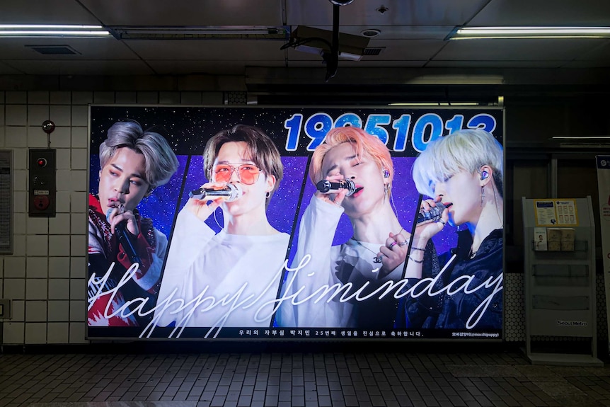 A brightly-coloured poster of K-pop stars in an underground subway.