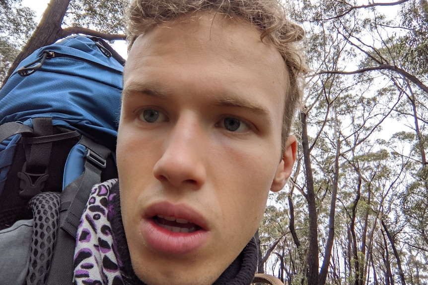 Close-up of a young man carrying a big backpack