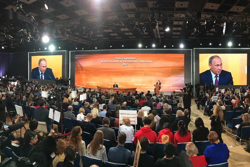 A wide shot of the annual news conference, with Vladimir Putin sitting on the stage.