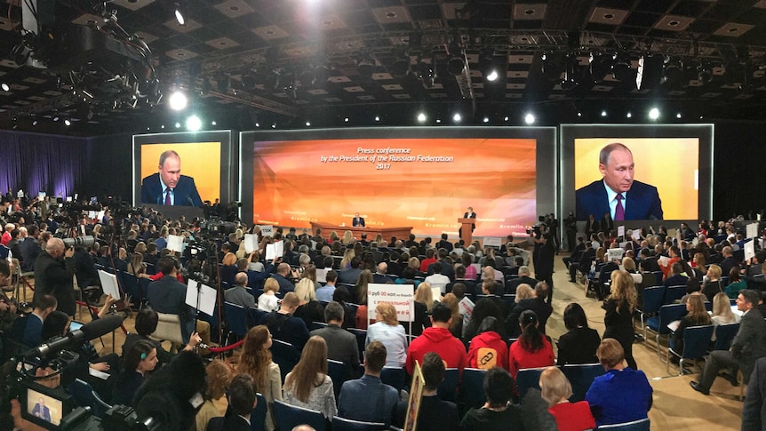 A wide shot of the annual news conference, with Vladimir Putin sitting on the stage.