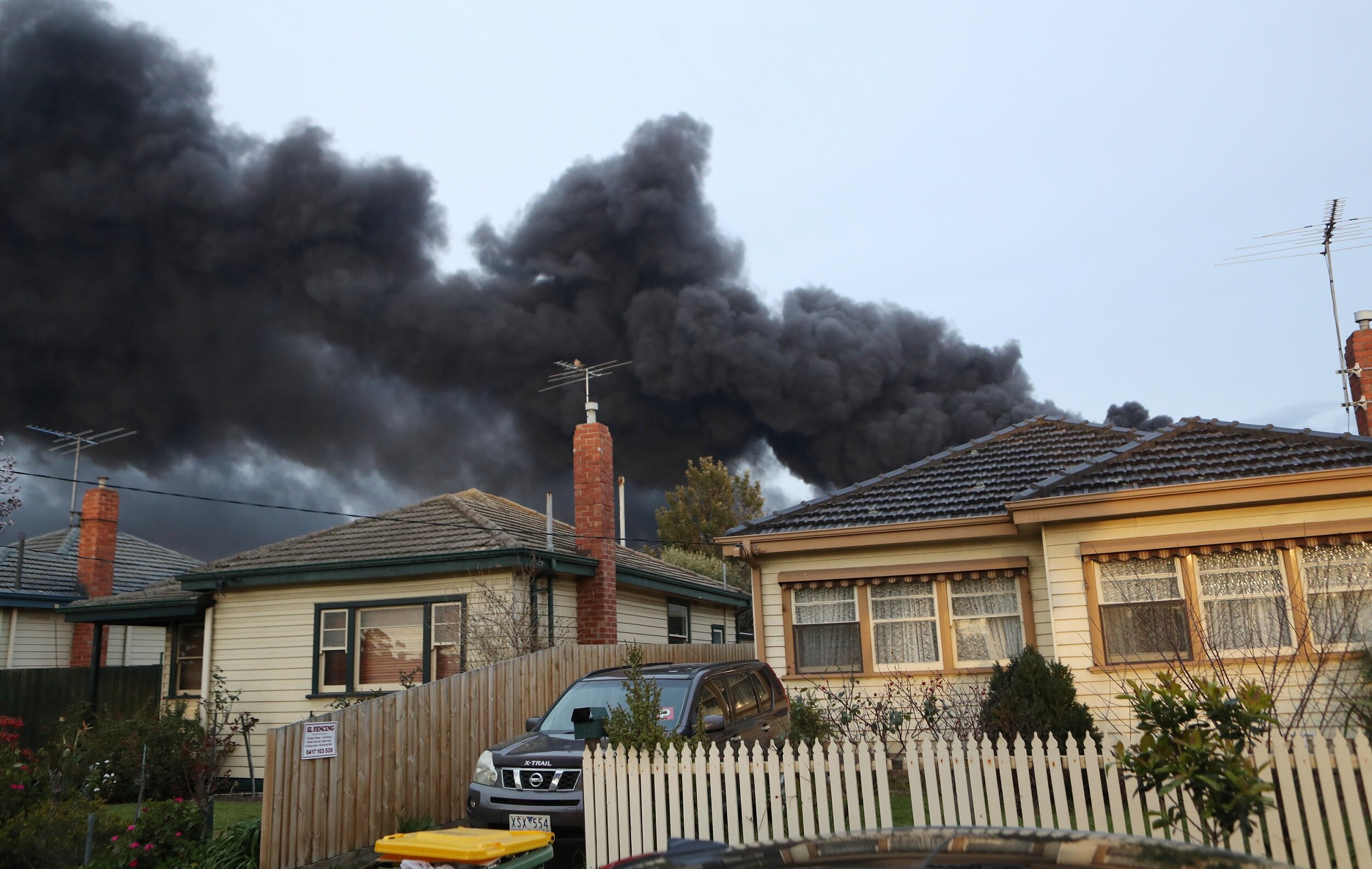 Thick, black smoke billows over the rooves of houses near a factory fire in West Footscray.
