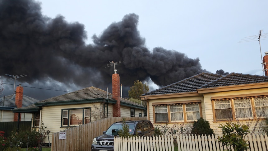 Thick, black smoke billows over the rooves of houses near a factory fire in West Footscray.