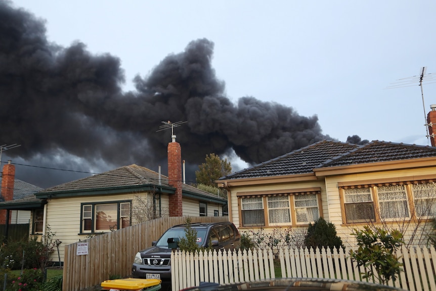 Thick, black smoke billows over the rooves of houses near a factory fire in West Footscray.