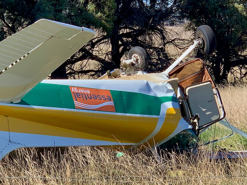 Close up of a small plane upside down in the field.