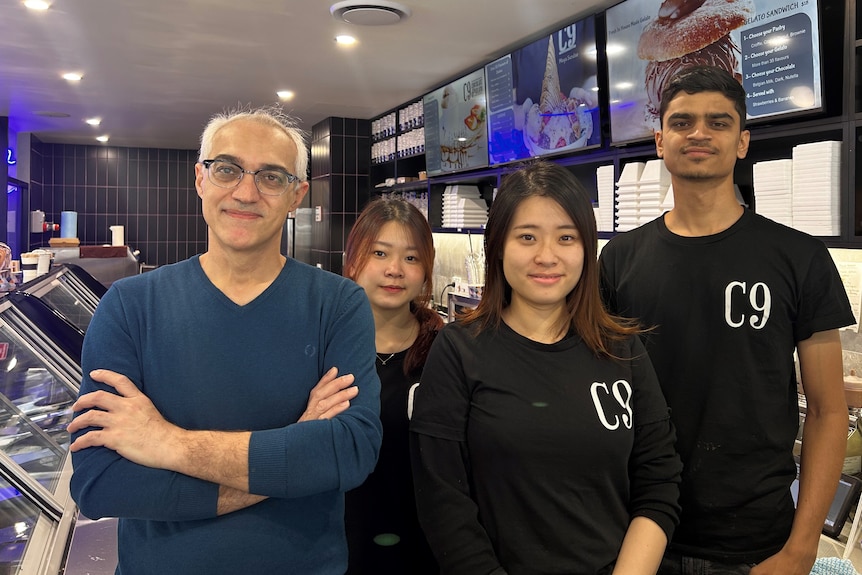 Four people stand smiling together in a gelato store.