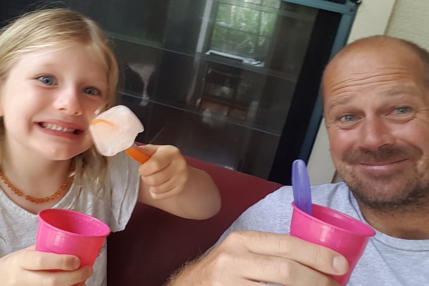 A man and a young girl eating ice cream out of pink cups