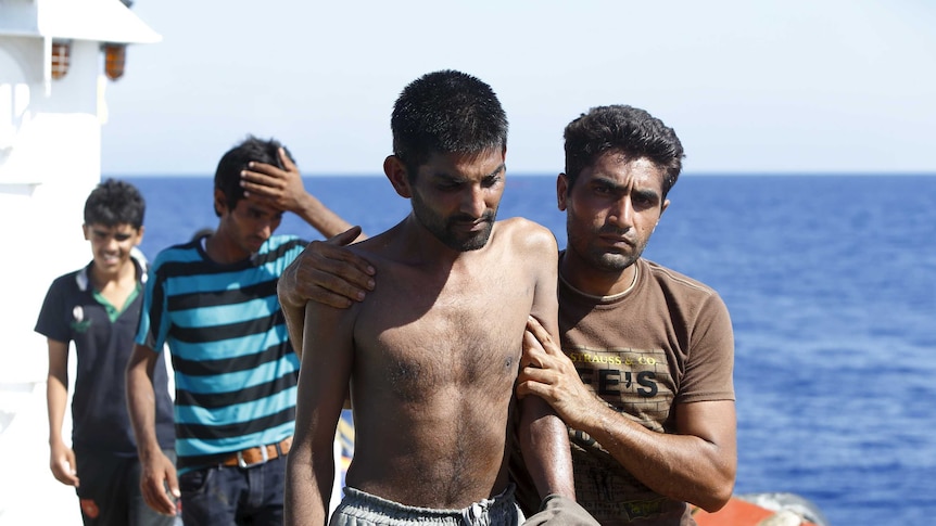 Migrants walk on the upper deck of the Migrant Offshore Aid Station ship MV Phoenix after being rescued