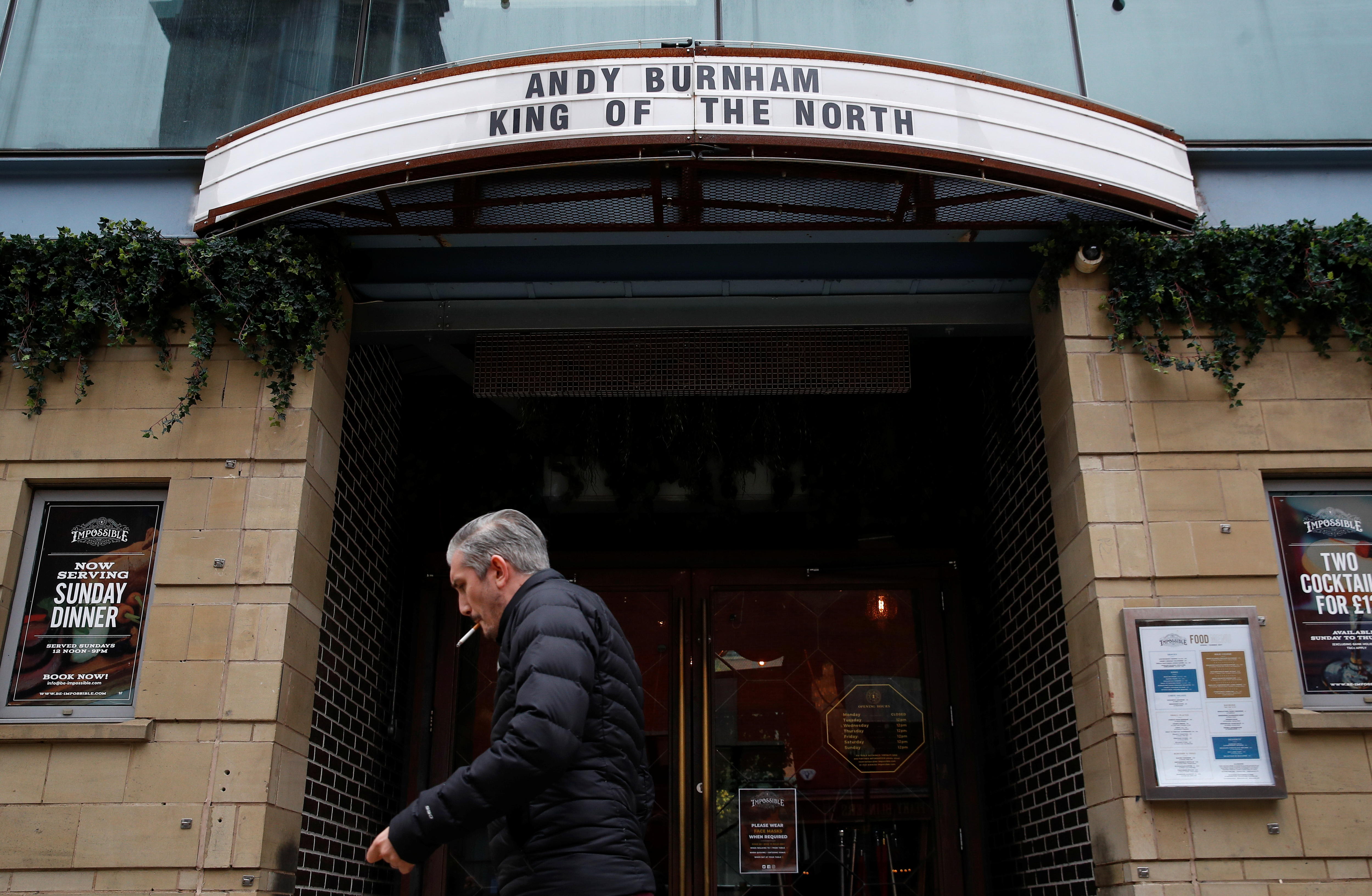 A man walks past a sign that says 'Andy Burnham King of the North' 