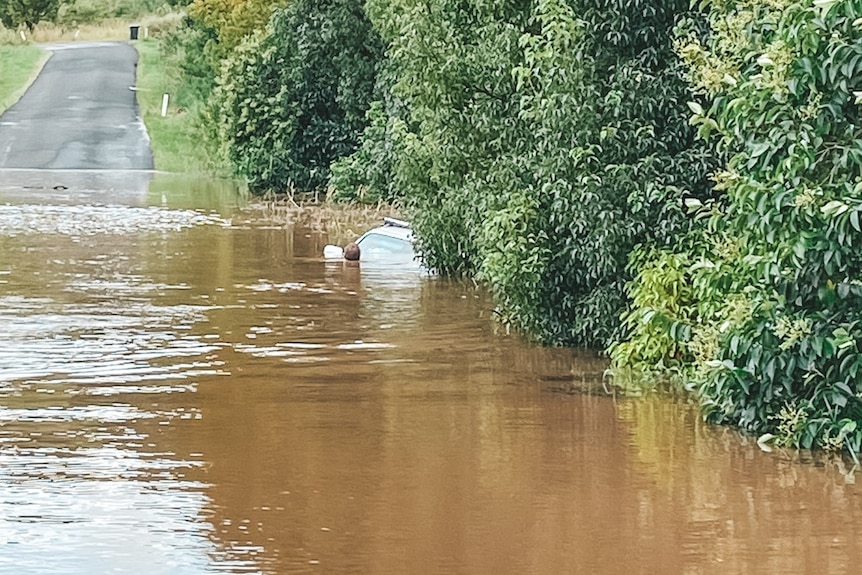 flooded car in distant of brown flood waters