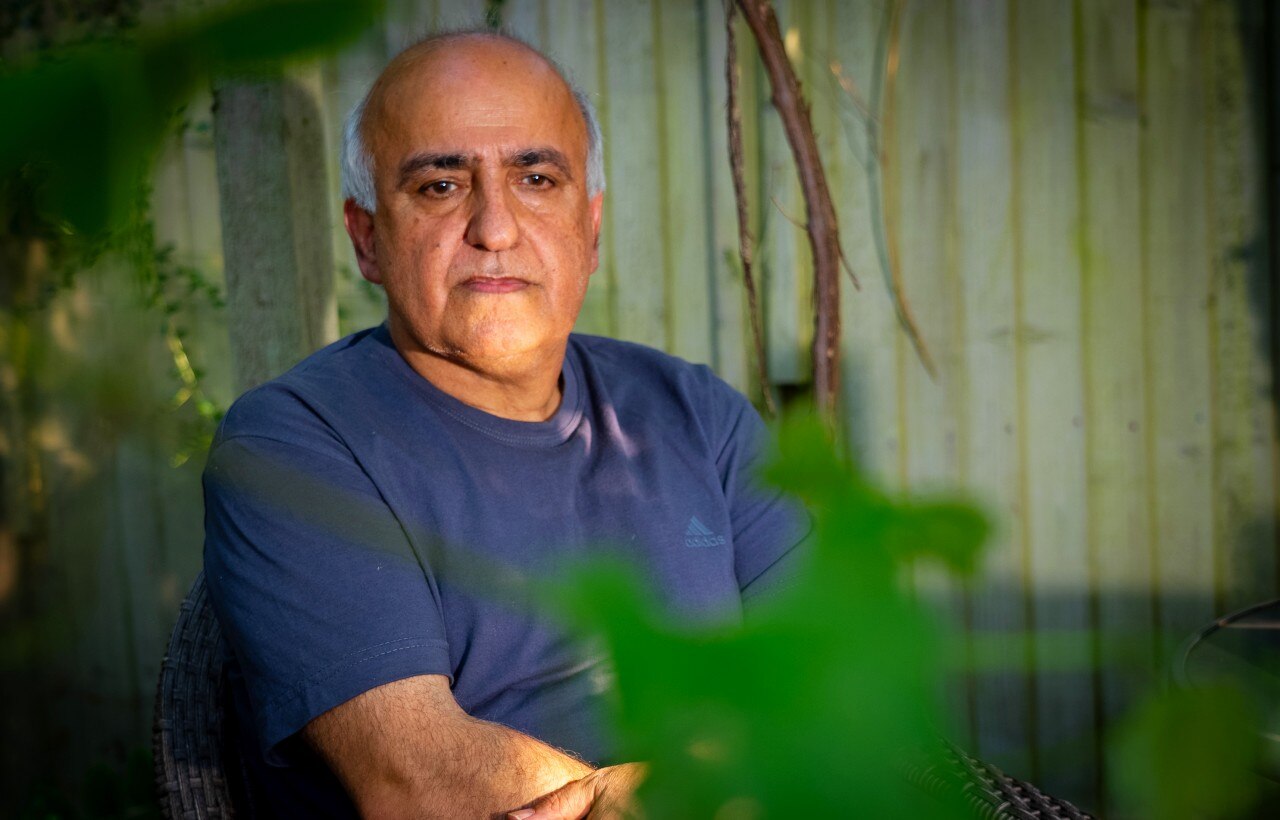 A man looks at the camera with a serious expression on his face