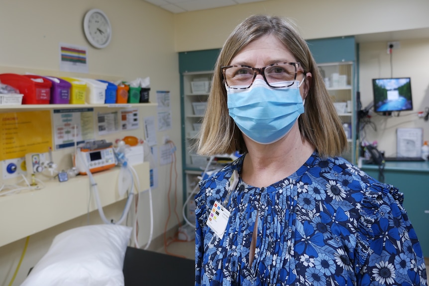 Leanne Kilpatrick stands in front of medical equipment, wearing a face mask