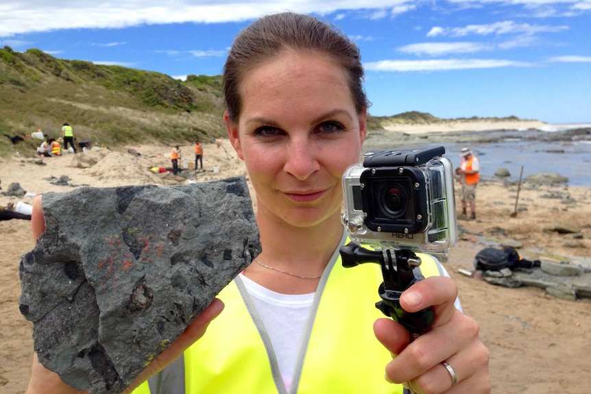 Doctor Kaja Antlej holds up a fossilised dinosaur tooth