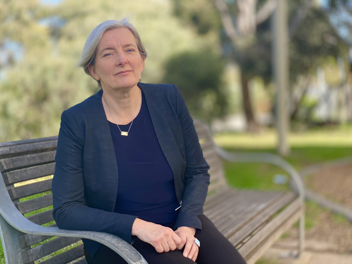 Kathleen Maltzahn está sentada en un banco del parque con una expresión seria en el rostro.