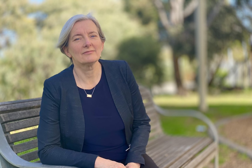 Kathleen Maltzahn sits on a park bench with a serious facial expression.