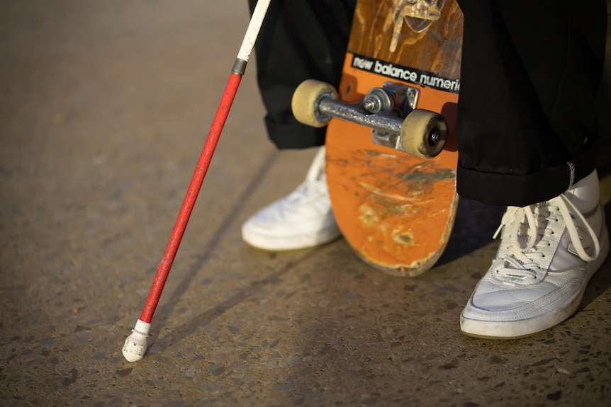 a close-up of a white cane with a red on the bottom and the underside of a skateboard