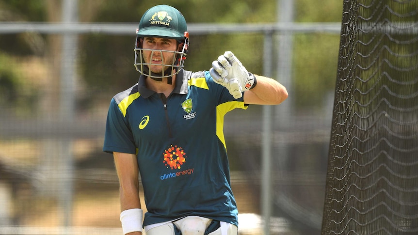 Batsman in pads and helmet at an Australian cricket team training session.