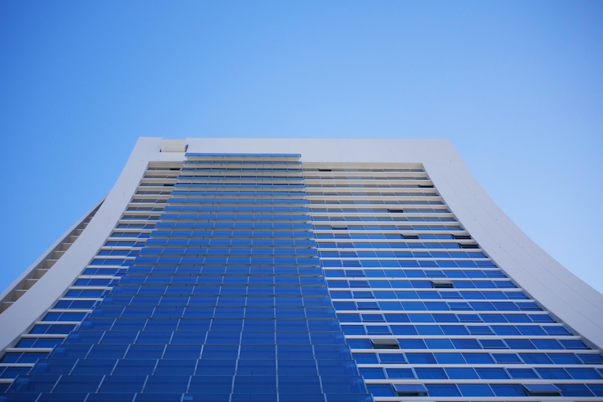 A photo aiming directly up a high-rise building. A bright blue sky is behind it.