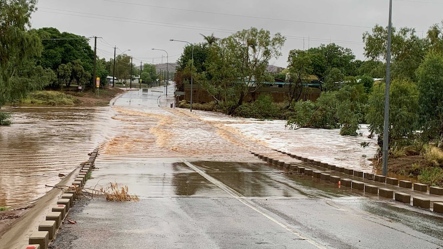 Floodwaters run across a road crossing a river.