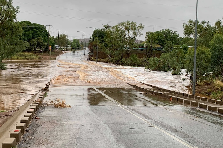 Floodwaters run across a road crossing a river.