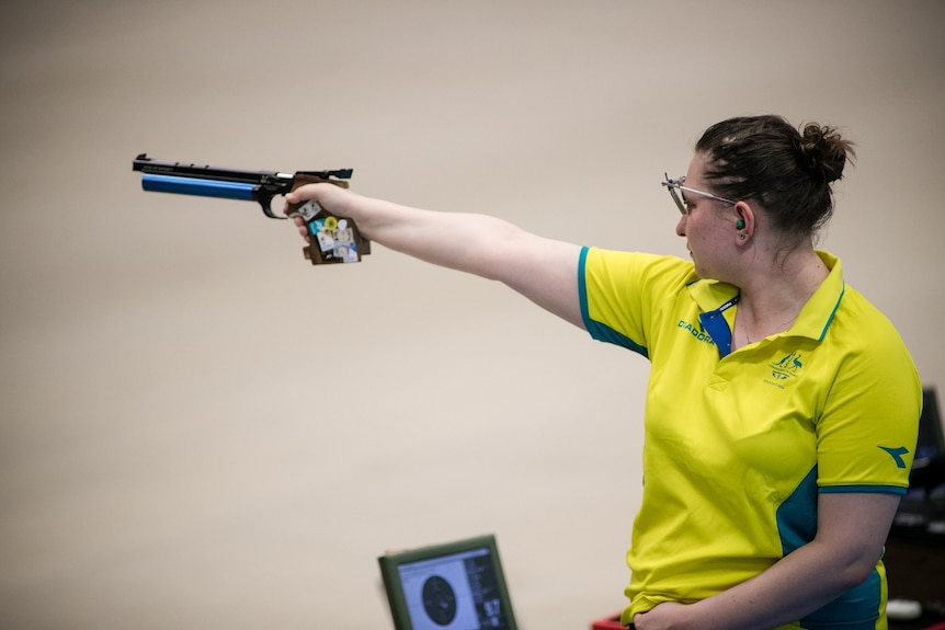 Shooter Elena Galiabovitch stands side on and points her gun.