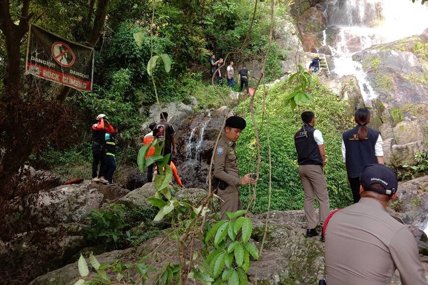 Police and rescuers retrieving the body of a tourist who fell down a waterfall.