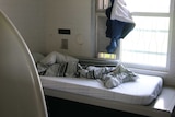 An unmade bed next to barred windows in Banksia Hill Detention Centre.