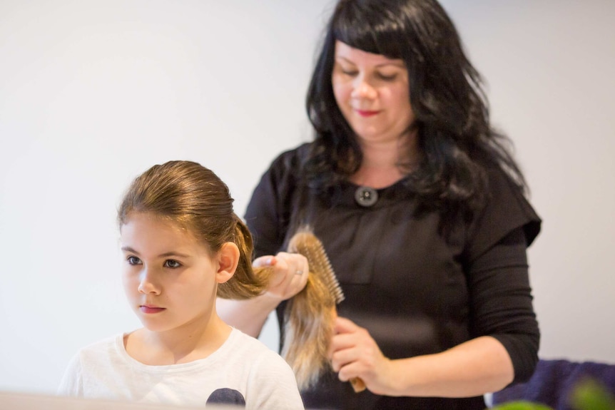 Charlotte brushes her daughter's hair before school.