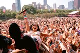 A woman holding a microphone looks at the camera while crowdsurfing on her back at a music festival