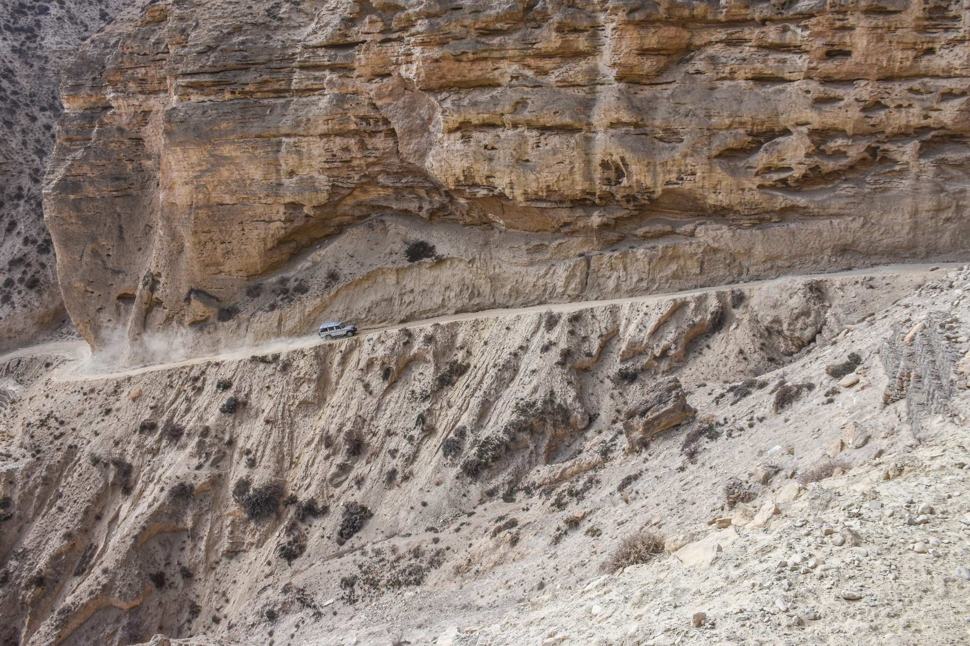 A jeep struggles precariously up a hill in a cliff face