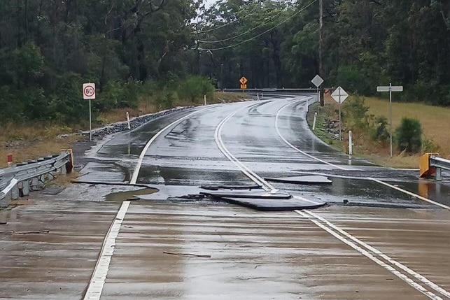 A road that has been damaged leading onto a bridge.