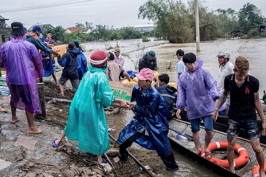 Local residents and volunteers deliver aid packages to residents by boat.