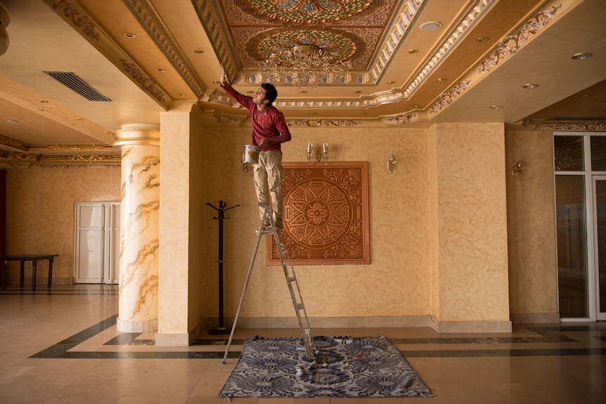 Man painting ceiling of hotel.