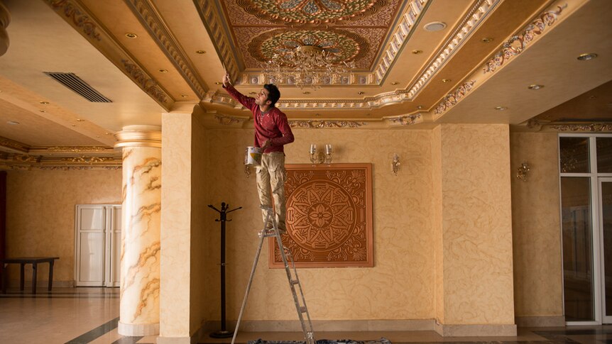 Man painting ceiling of hotel.