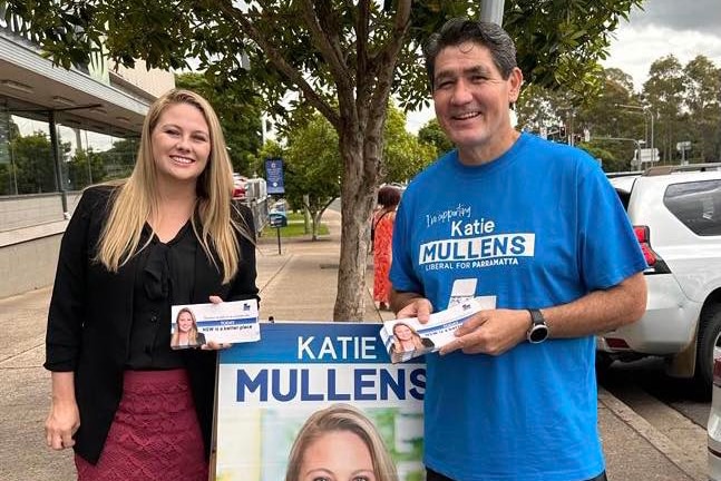 a woman and another man campaigning ahead of an election and handing out how to votes